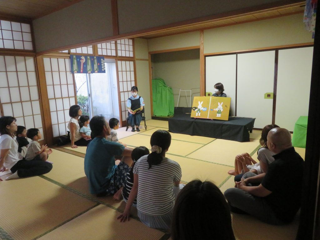 人々が和室で物語を聞いている様子を描いた画像。