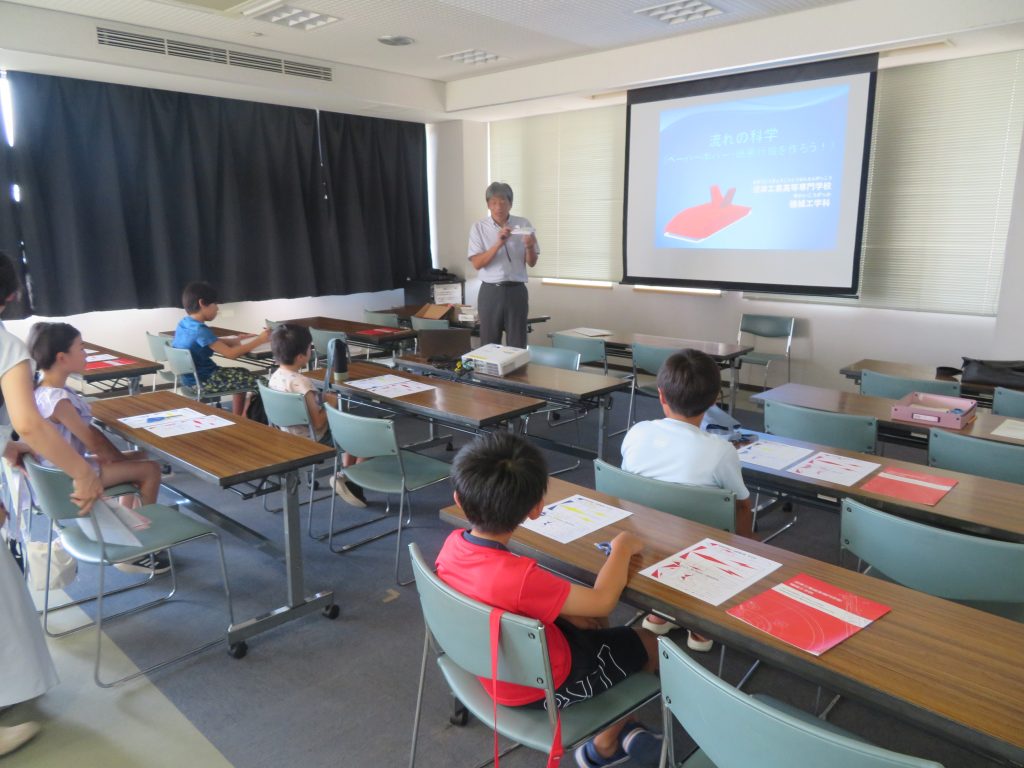 教室で教師が生徒に向かって説明している様子を示した画像