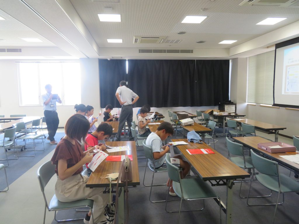 教室で子どもたちが机に向かって何かに取り組んでいる様子が写っている画像。