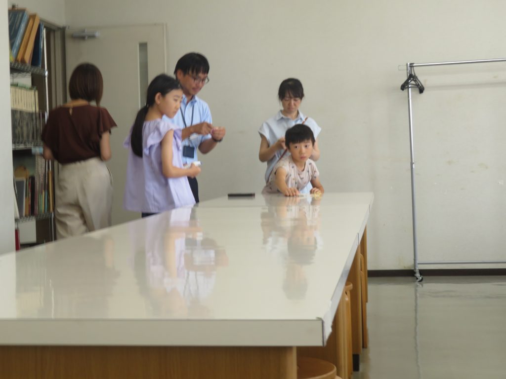 テーブルの周りに数人の子供と大人がいる室内の風景