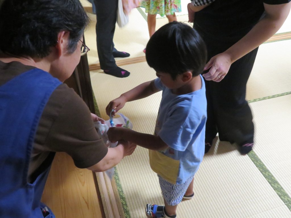 子供が大人と一緒に何かを手に取っている場面の写真です