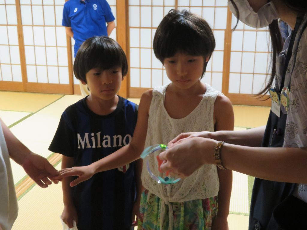 子供たちが大人と一緒に手をつないでいる場面の写真。