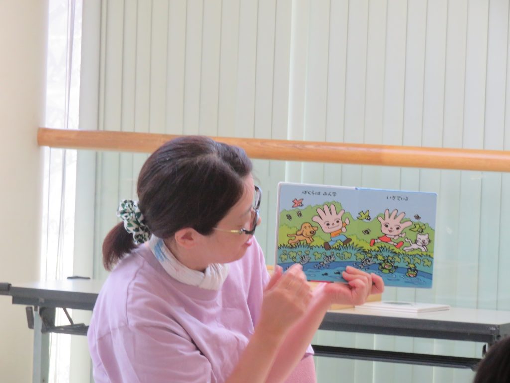 女性が絵本を指差しながら話している様子が写っています。