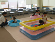 子供たちがカラフルなプールで遊んでいる室内の風景。