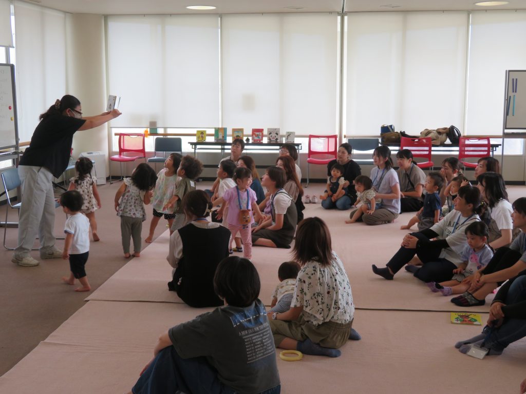 子供たちが集まっている教室で、大人が何かを見せている様子。