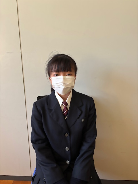 制服を着た人物が壁の前に座っている画像です