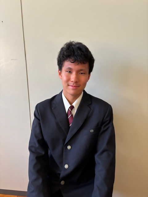 制服を着た男子学生が前を向いて座っている画像