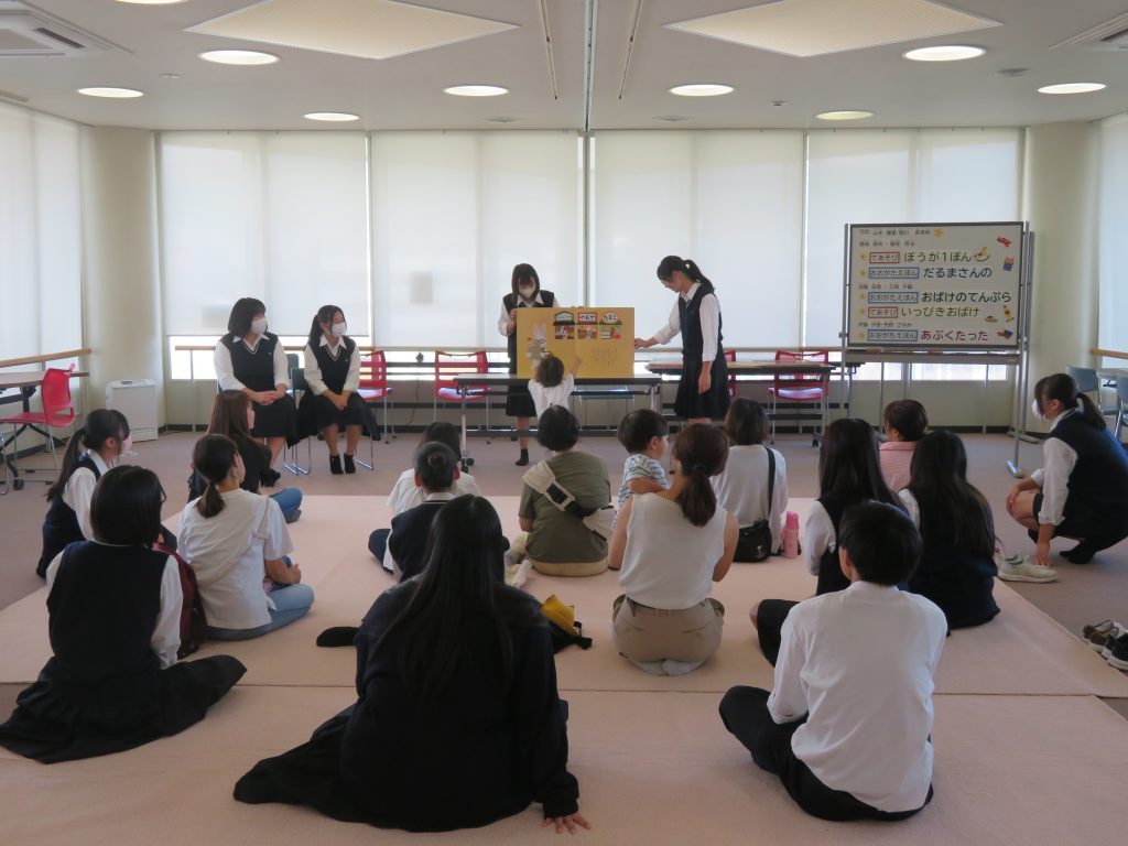 教室で座っている子供たちと話をしている大人たちの様子を捉えた写真。