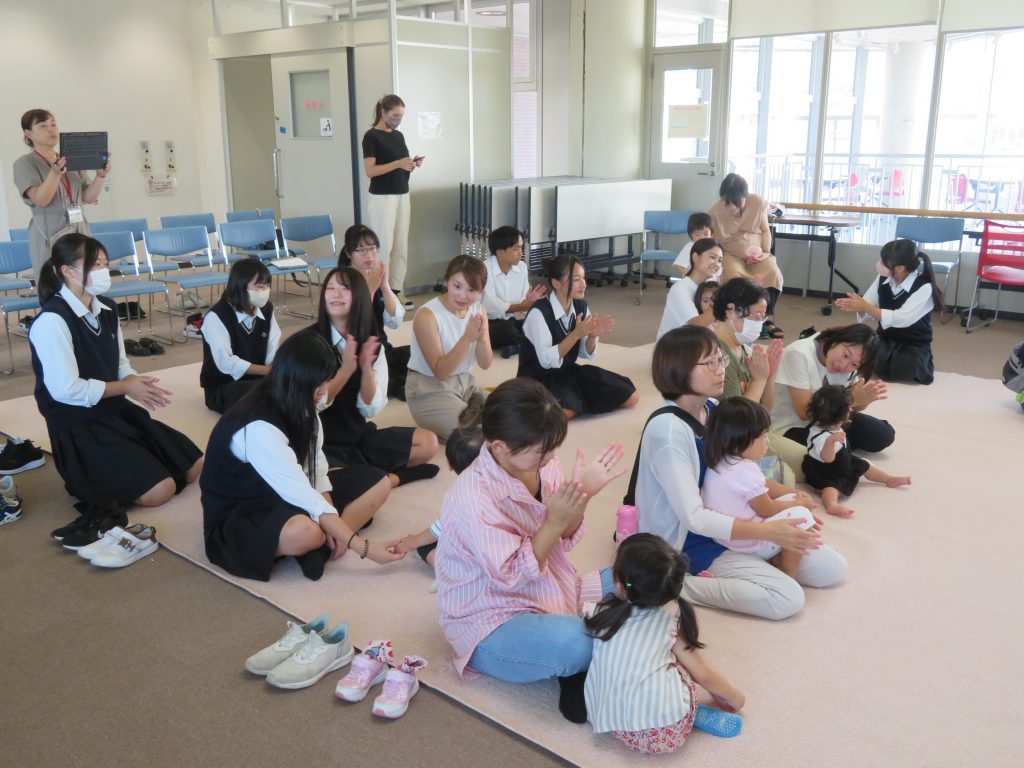 子供と大人が集まり、楽器を持って楽しんでいる様子の室内の活動。