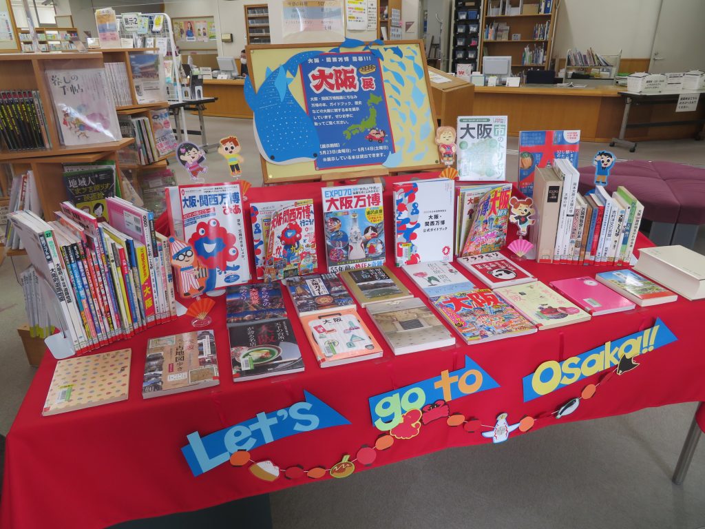 テーブルの上に並べられた多種多様な本とポスターが置かれている様子。