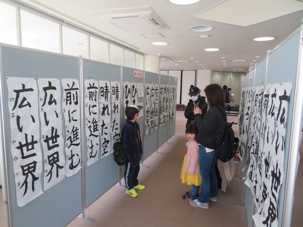 書道作品が展示されている部屋で、数人の子供たちが作品を見ている様子。